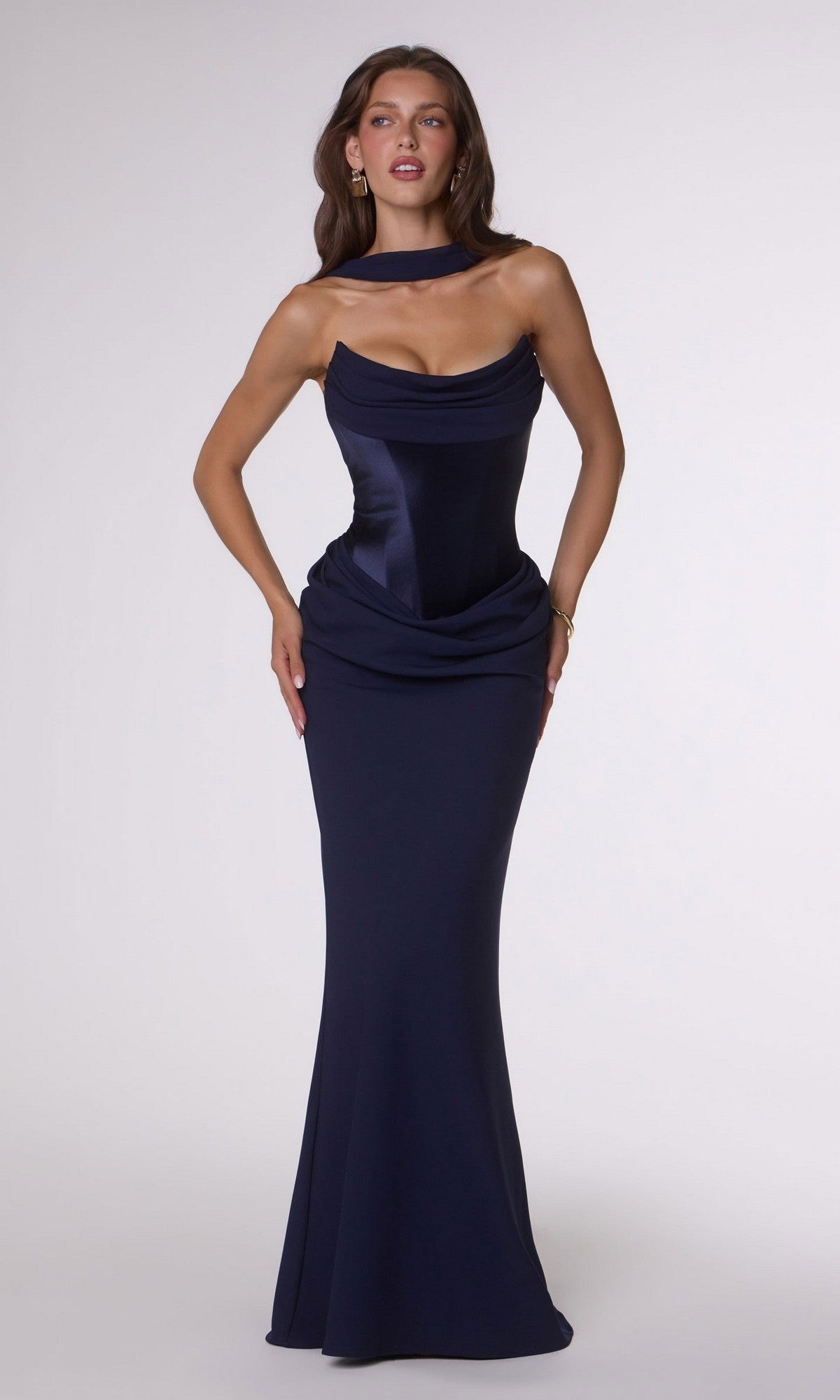 A woman poses against a plain light background wearing the Amoris T732 Long Prom Dress in navy, featuring a form-fitting stretch satin design with a draped neckline, corset back, and floor-length skirt.